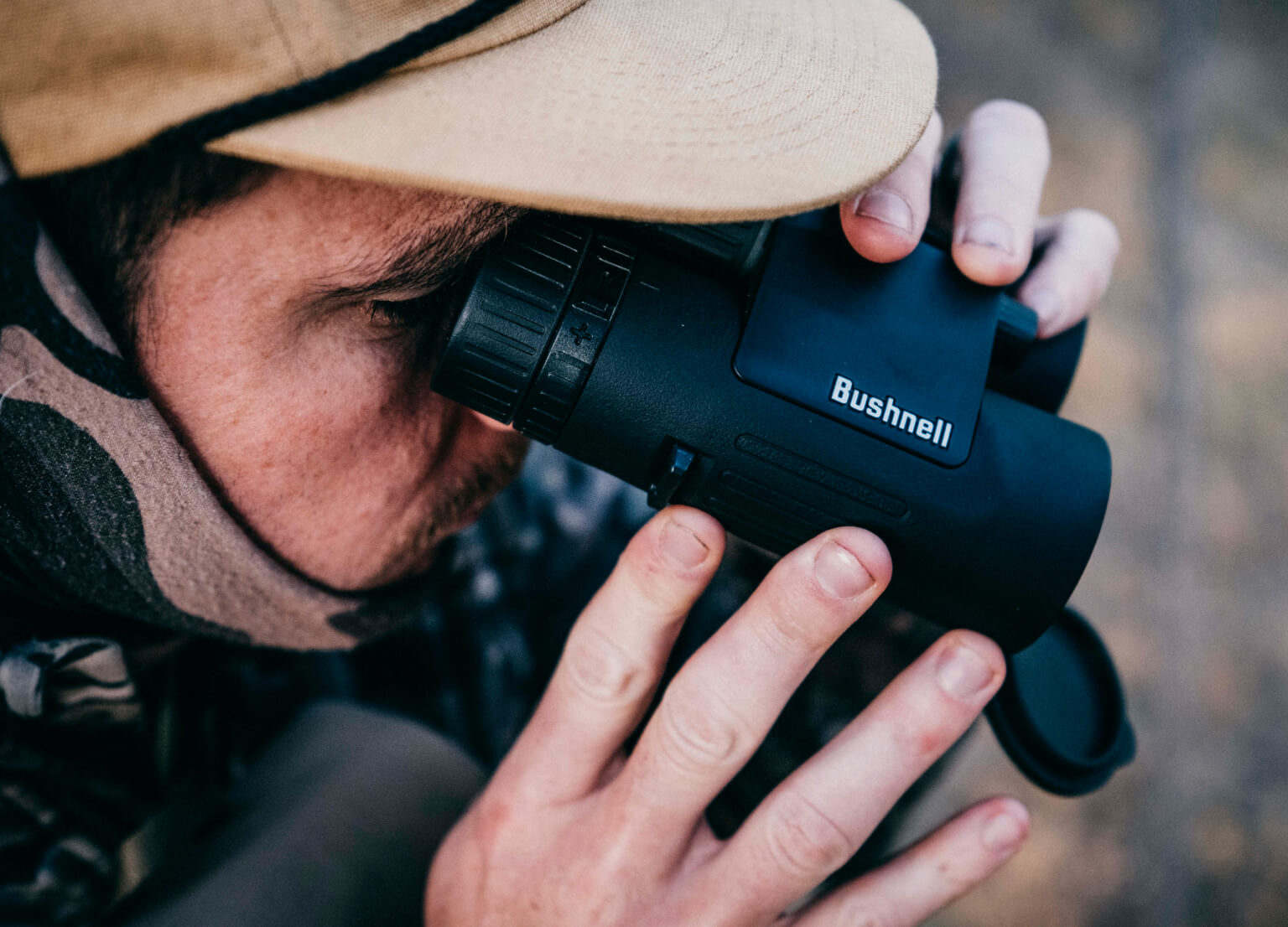 Close-up of man in the woods looking through Bushnell Binoculars