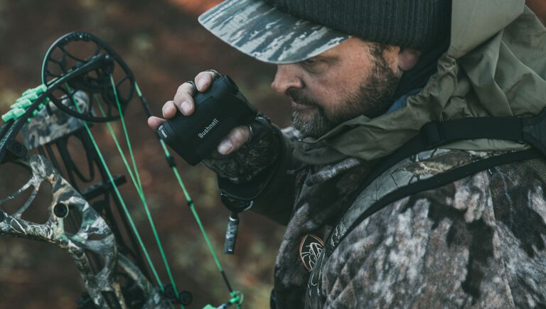 man shooting archery holding a rangefinder